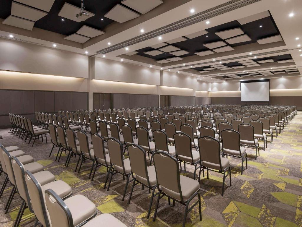 an empty room with rows of chairs and a screen at Pullman Sao Paulo Guarulhos Airport in Guarulhos