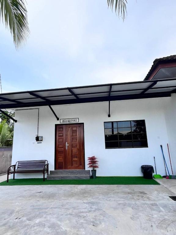 a white building with a wooden door and a bench at KafHa Homestay in Kuala Terengganu