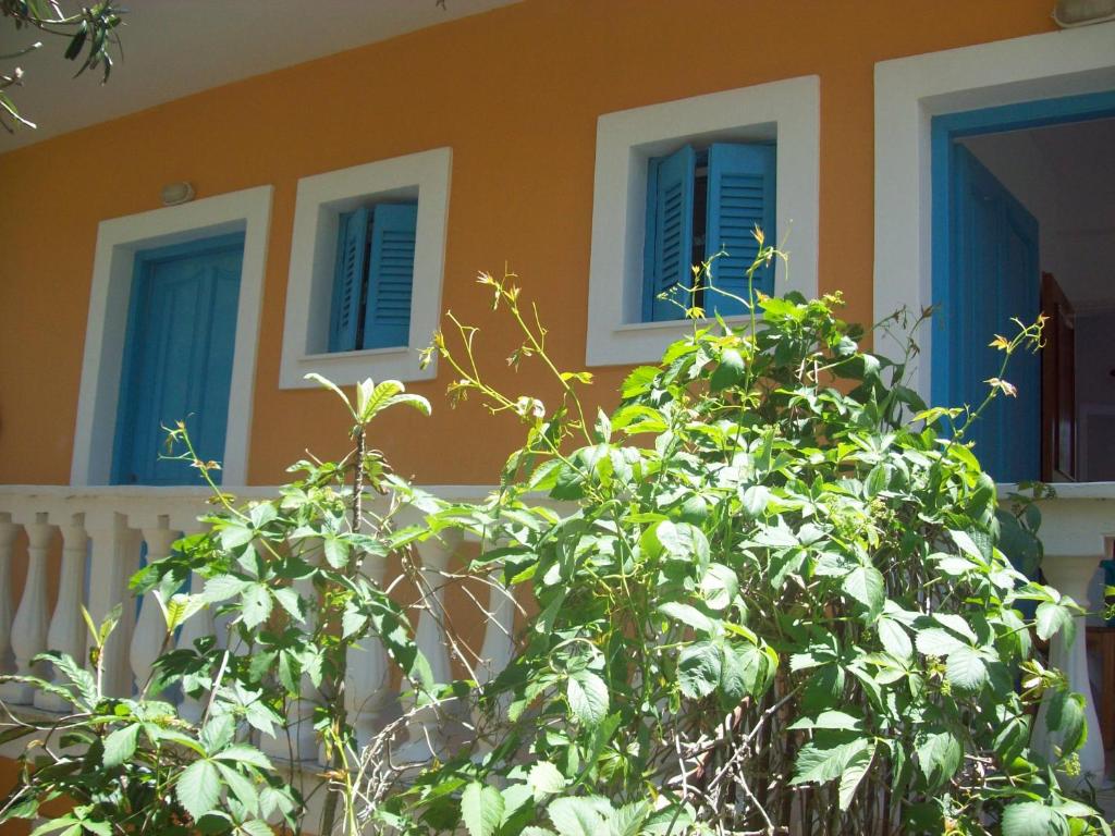 une maison avec des fenêtres bleues et une brousse devant elle dans l'établissement Villa Vania, à Vitalades