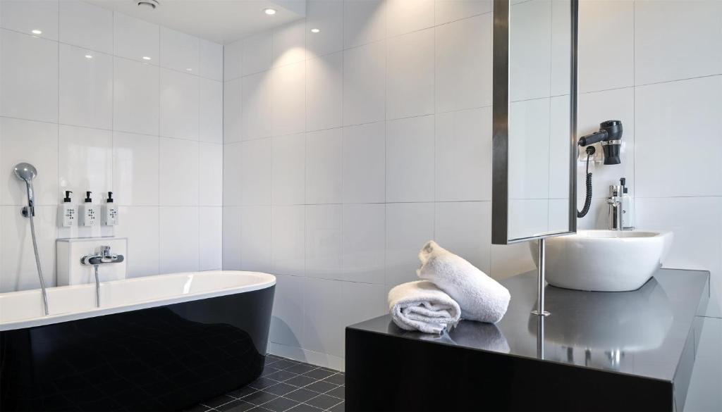 a white bathroom with a tub and a sink at Scandic Malmen in Stockholm
