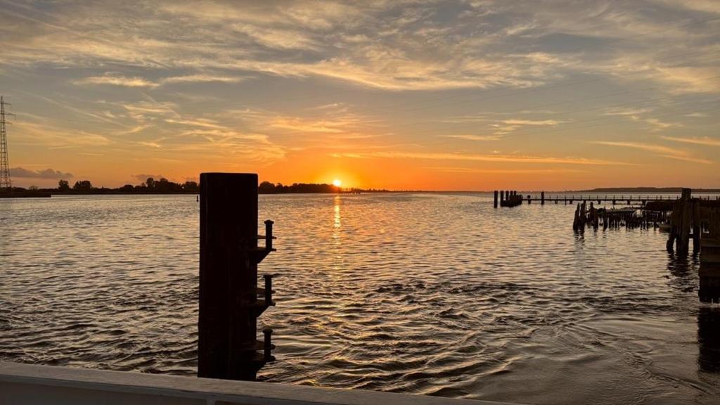 a sunset over a body of water with a dock at Ferienwohnung Windhund in Dornum
