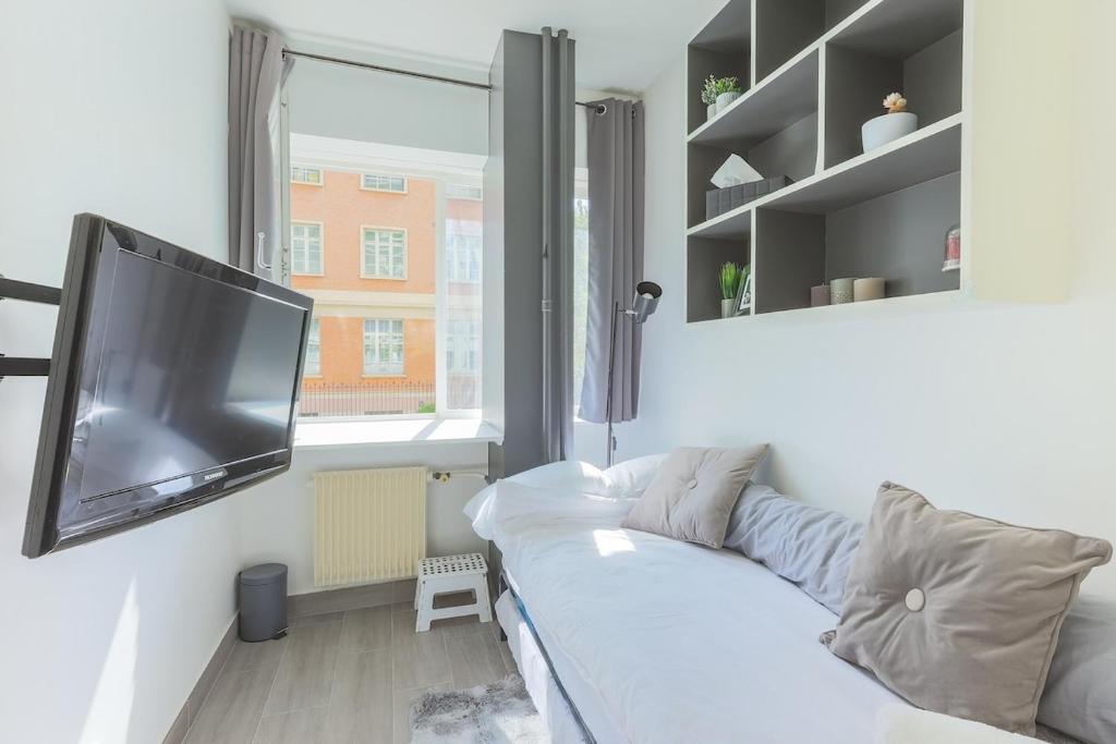 Il comprend un salon doté d'un canapé blanc et d'une télévision à écran plat. dans l'établissement Lovely Studio in Paris XVI, à Paris