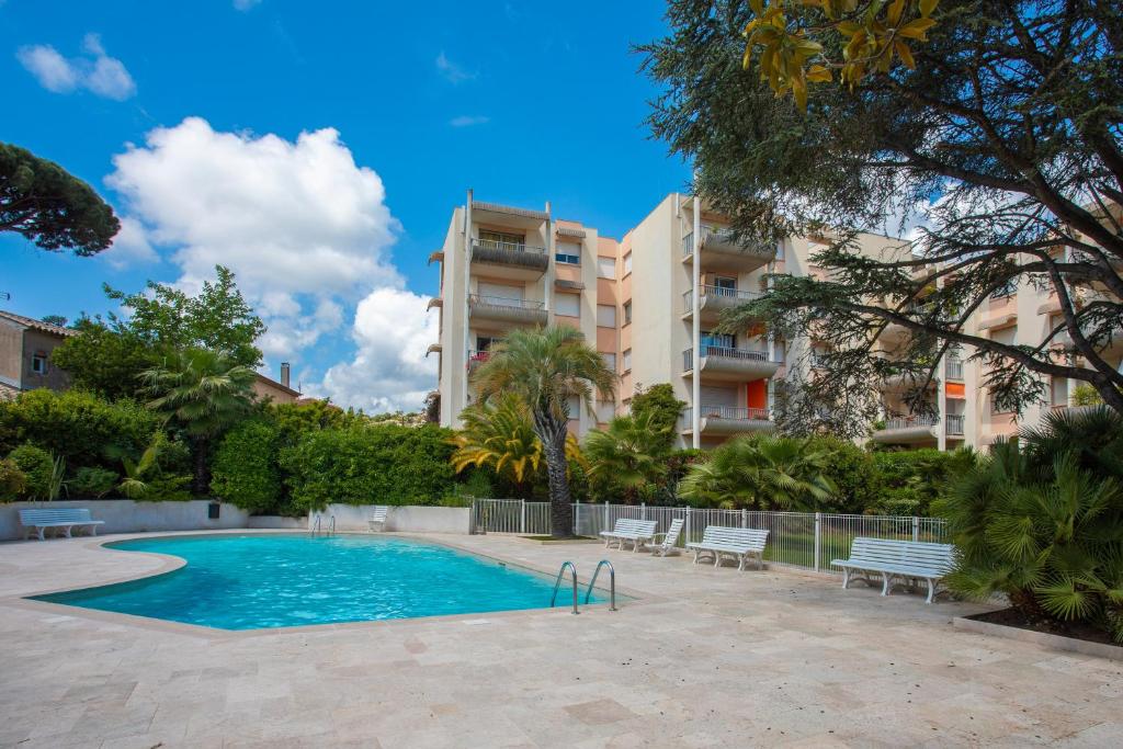 une piscine avec des chaises et un bâtiment dans l'établissement Les Balcons Fleuris, à Sainte-Maxime