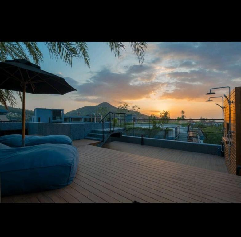 eine Couch auf einem Deck mit einem Regenschirm in der Unterkunft City Gate Apartments Kamala Beach Phuket Thailand - LMY in Ban Nong Chaeng