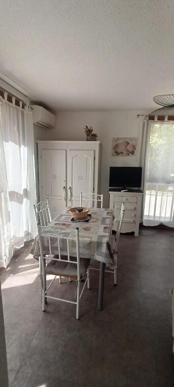 une salle à manger avec une table, des chaises et une télévision dans l'établissement Appartement climatisé Parc Paradis 150 m des thermes, à Gréoux-les-Bains