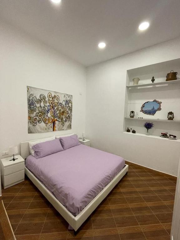 a bedroom with a purple bed and a painting on the wall at Violet House in Palermo