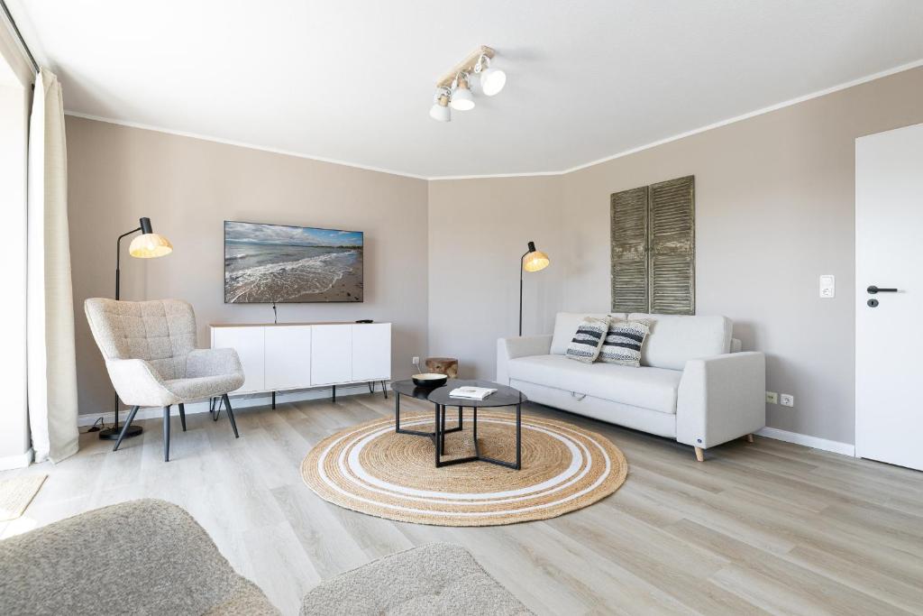 a living room with a couch and a chair at Haus Baltic Flat White in Laboe