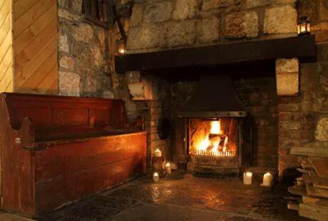 a brick fireplace with a fire in it at Skellys in Ballymahon