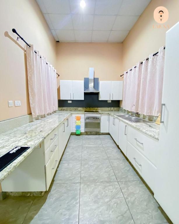 a kitchen with white cabinets and marble counter tops at La Luna Homes in Blantyre