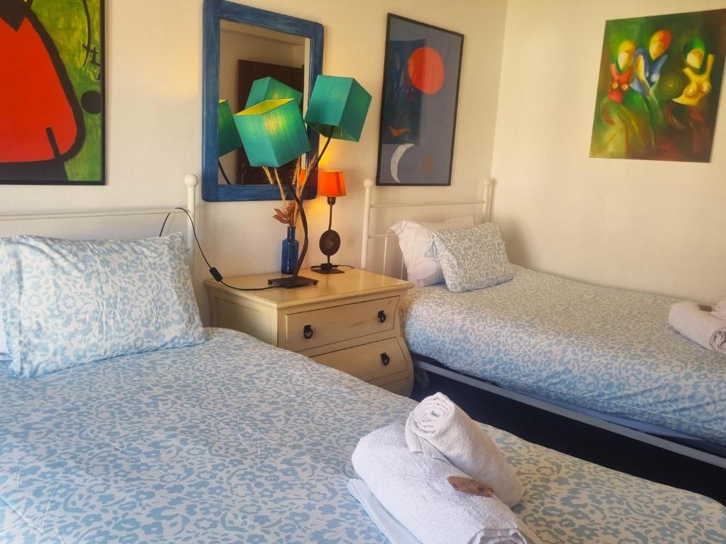 two beds in a room with paintings on the walls at CASA MILFONTES by Stay in Alentejo in Vila Nova de Milfontes