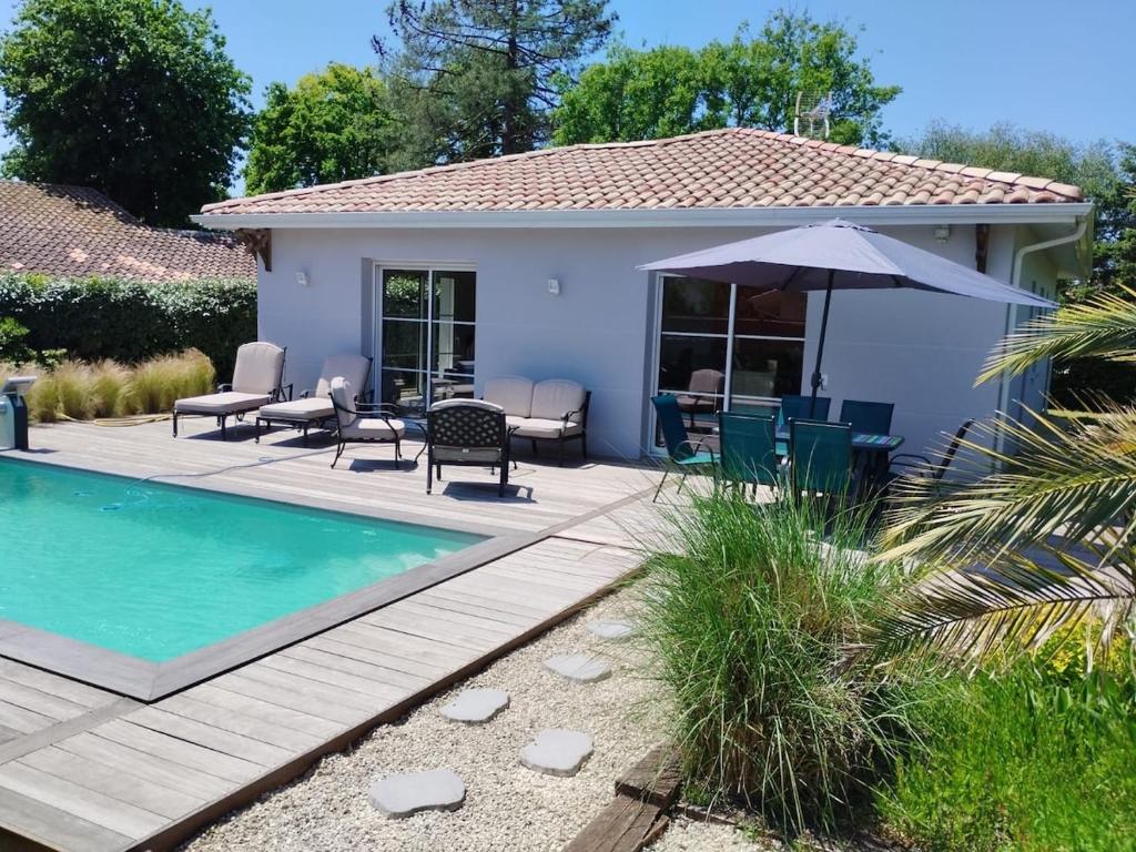 une cour arrière avec une piscine et une maison dans l'établissement Superbe Villa Bassin Arcachon - Piscine Chauffée, à Gujan-Mestras
