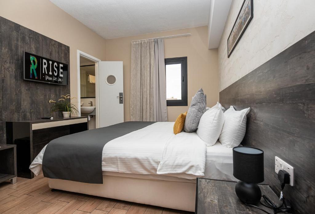 a bedroom with a large bed with white sheets and pillows at Rise Urban Art Hotel in Larnaca