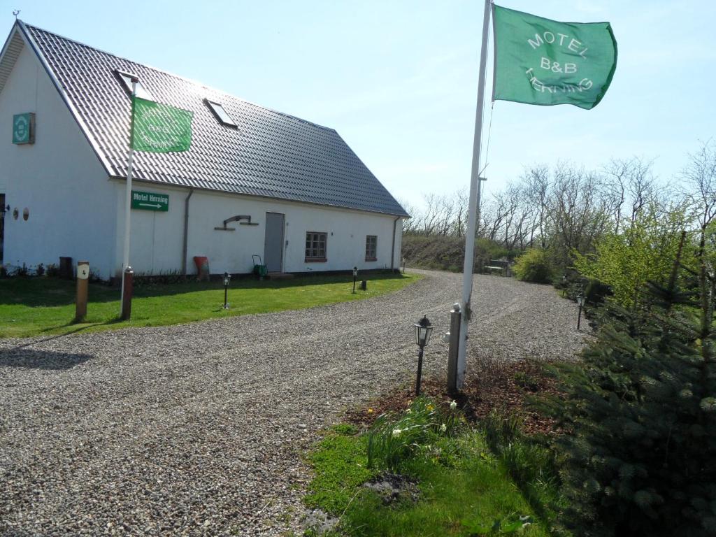 a flag on a gravel road next to a white building at Motel Herning in Kibæk