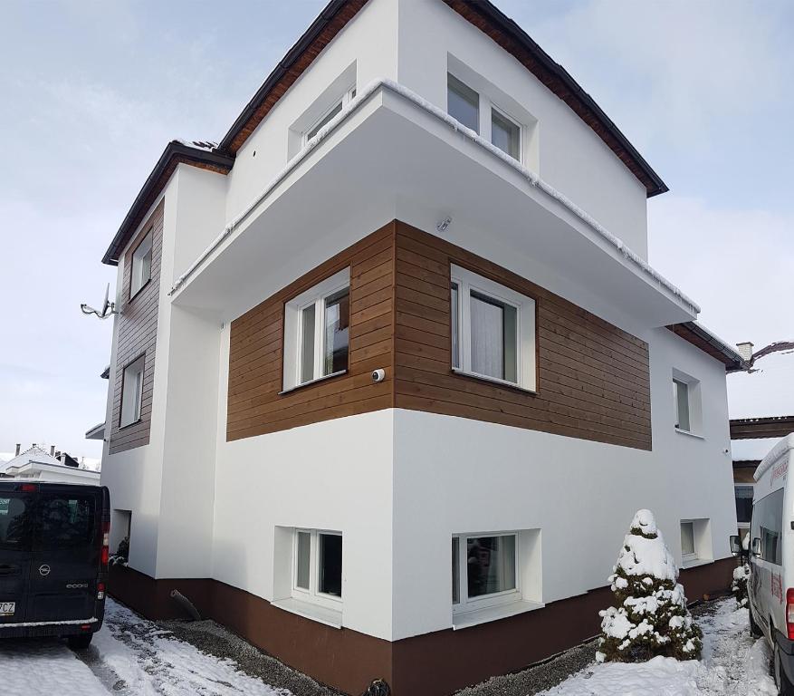a white and brown house in the snow at Family Tree rekreačný dom in Liptovský Mikuláš
