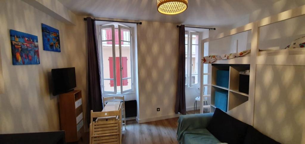 - un salon avec un canapé, une télévision et 2 fenêtres dans l'établissement Appartement en plein centre de Collioure à 30 mètres de la plage, à Collioure