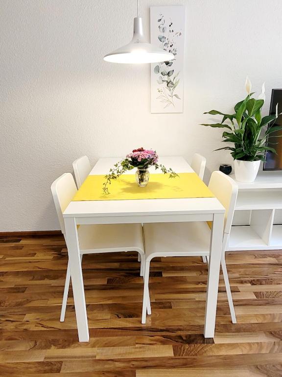 a white dining room table with a vase of flowers on it at Top2 Apartmenthaus Sonnenschein in Dornbirn