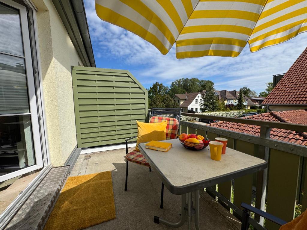 a table with a bowl of fruit on a balcony with an umbrella at Altes Wasserwerk App 15 in Wustrow