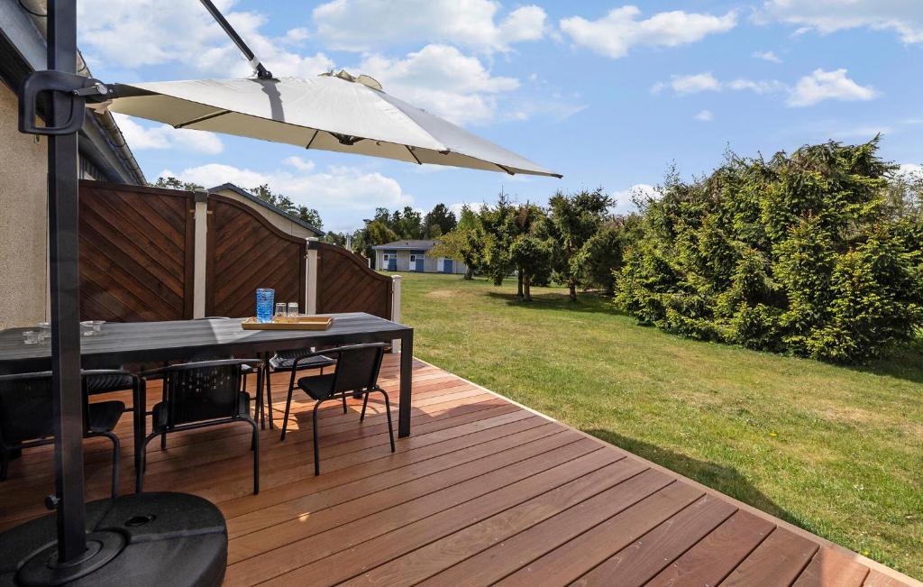 Una terraza de madera con una mesa y una sombrilla. en Gorgeous Apartment In Nexø With Sauna, en Neksø