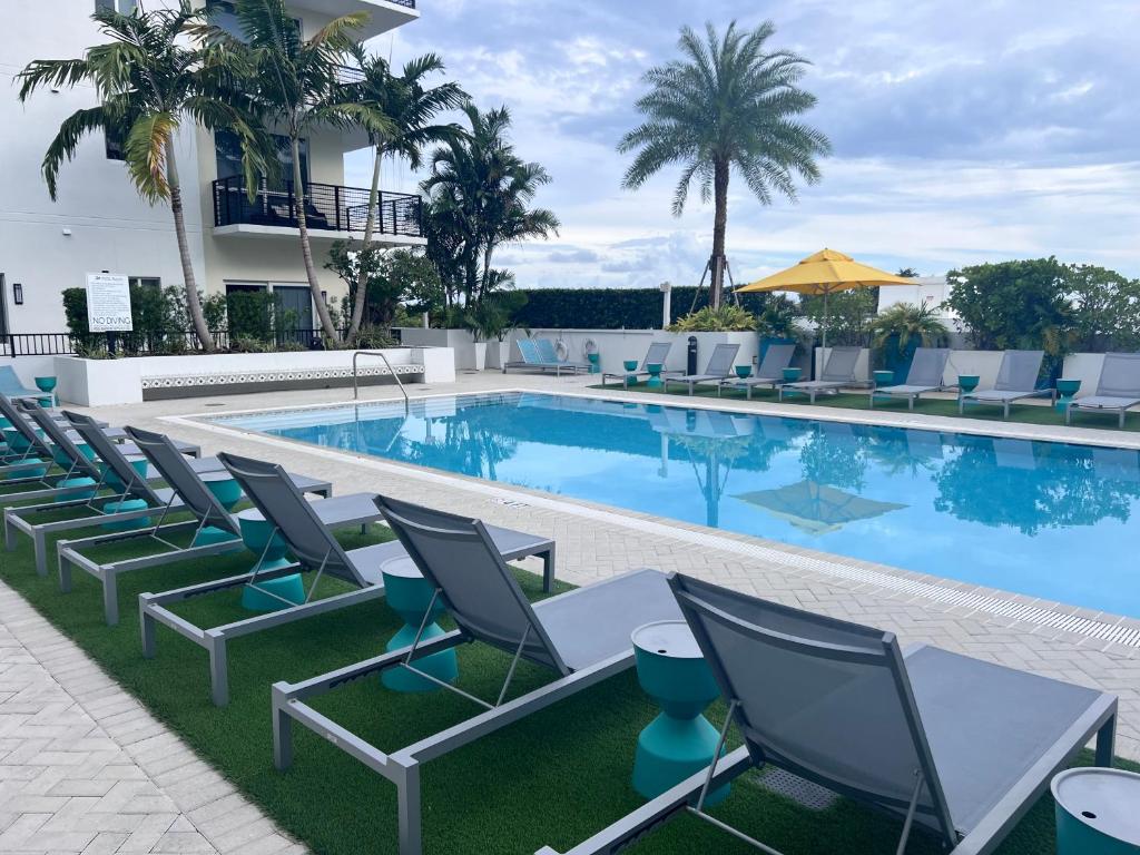une piscine avec des chaises et une table et un bâtiment dans l'établissement Master Bedroom In CALLE OCHO, à Miami