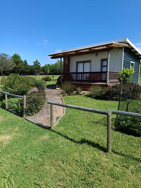 ein Haus mit einem Zaun vor einem Hof in der Unterkunft Sage Cottage in Wildernis
