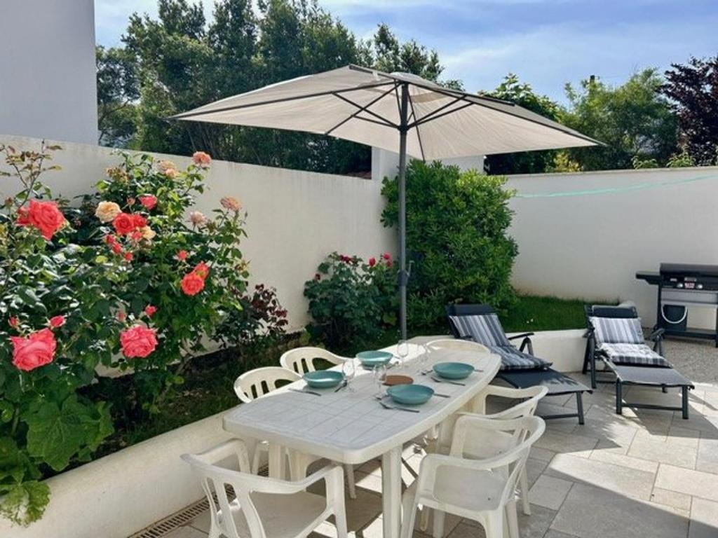une table et des chaises avec un parasol sur une terrasse dans l'établissement Appartement avec terrasse, 2 chambres, proche plage - 4 pers - FR-1-494-198, à Royan