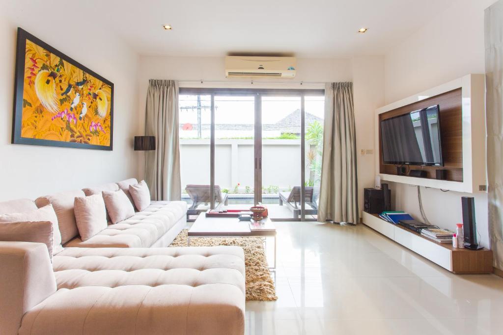 a living room with a couch and a tv at Honeymooner Pool Villa@Seastone in Bang Tao Beach