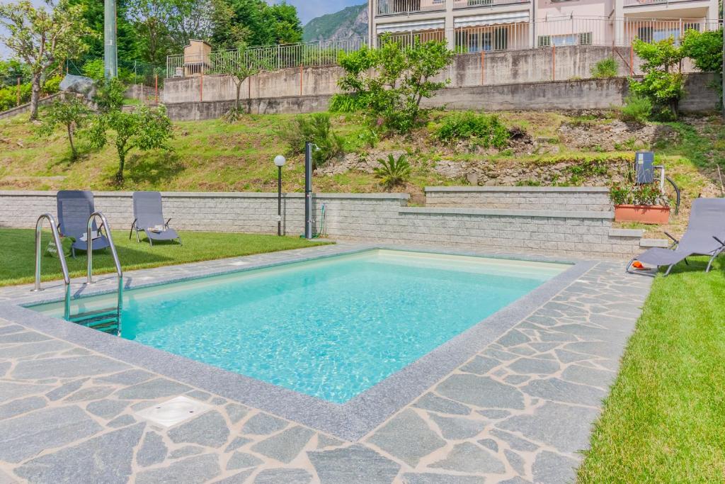 a swimming pool in a yard with two chairs at Sweet Caroline in Lierna