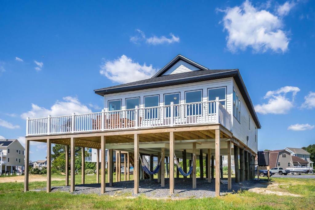 Una casa sobre postes de madera con un balcón. en Pier Pressure, en Greenbackville