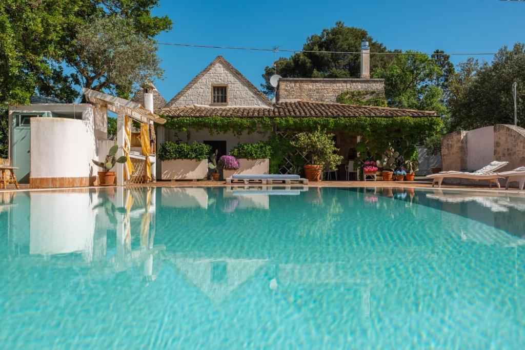 a large swimming pool with a house in the background at Trulli Volpe in Alberobello