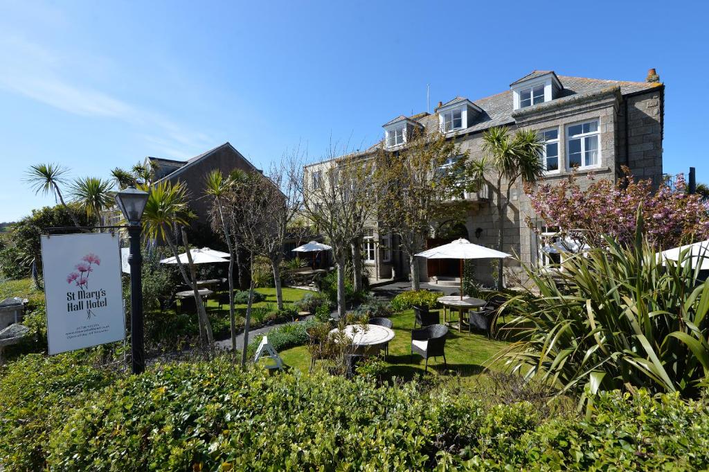 a hotel with tables and umbrellas in a garden at St Marys Hall Hotel in Hugh Town