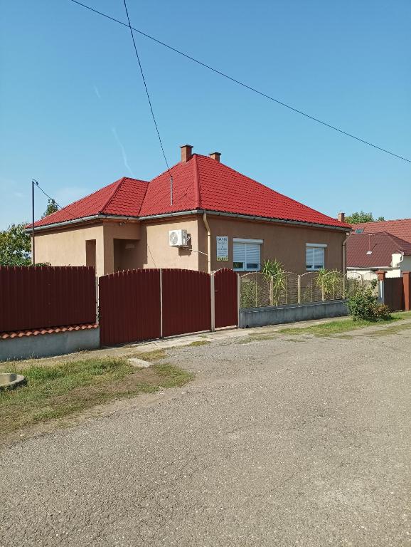 a house with a red roof and a fence at Bandi Vendégház in Verpelét