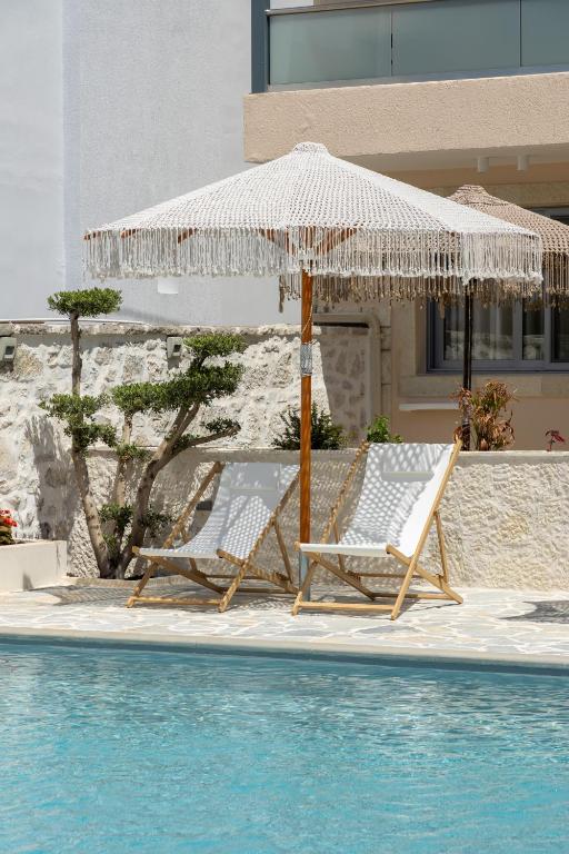 duas cadeiras e um guarda-sol junto a uma piscina em Dimitri Hotel em Himare