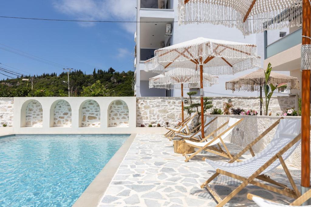 uma piscina com cadeiras e guarda-sóis ao lado de um prédio em Dimitri Hotel em Himare