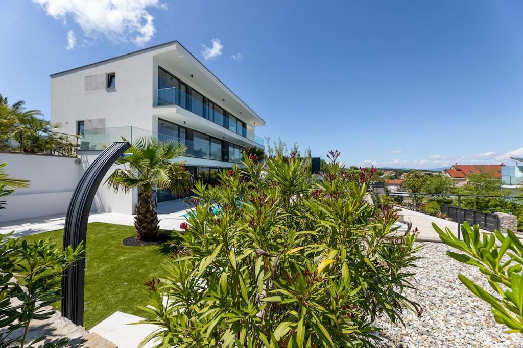a white house with palm trees in front of it at Brand new apartment "Z" with swimming pool by EL-PI Tours in Vantačići