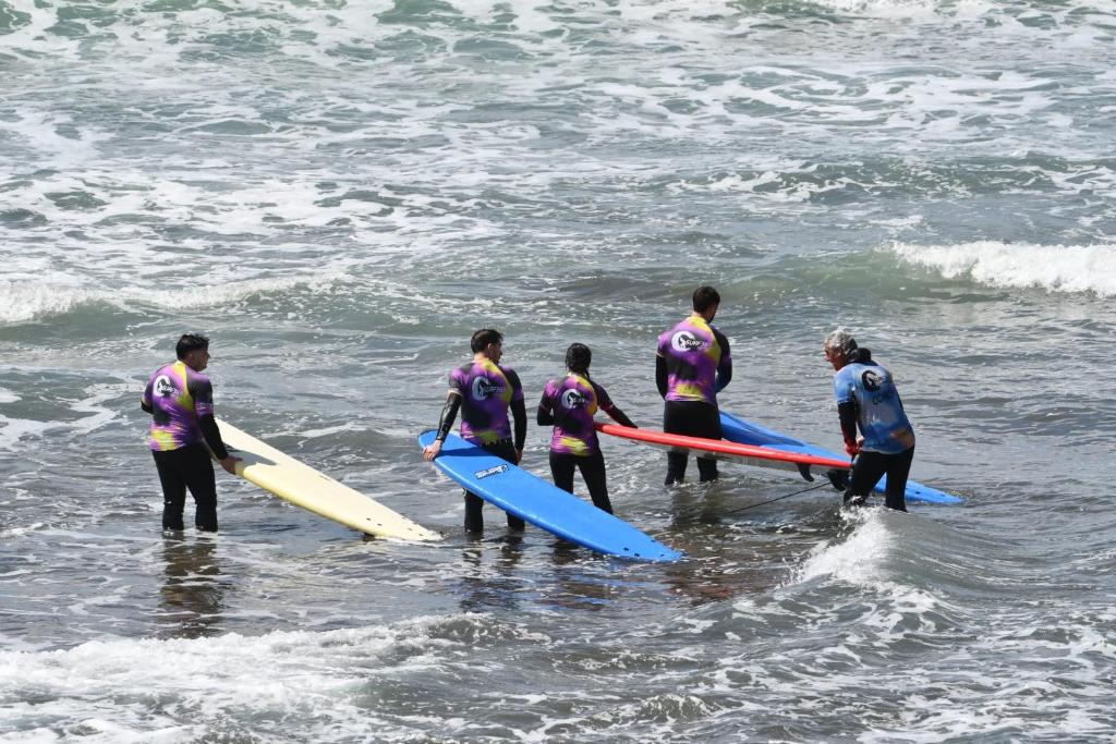 a group of people standing in the ocean holding surfboards at 70's Hostel in Ericeira