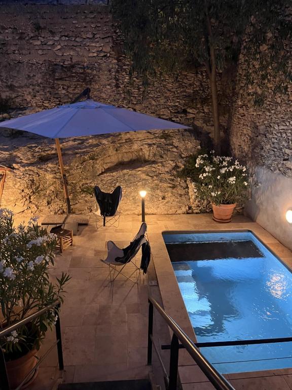 une piscine avec un parasol, une table et des chaises dans l'établissement Maison de village en Provence Luberon, à Saint-Saturnin-lès-Apt