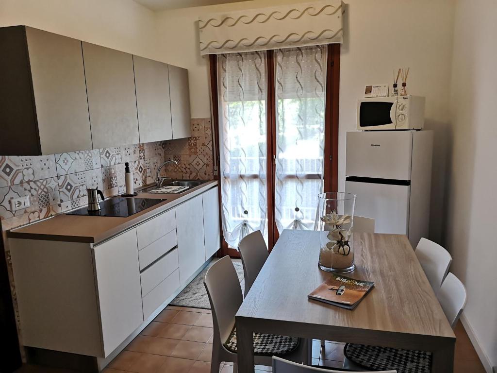 a kitchen with a table and a white refrigerator at SummerJoy in Bibione