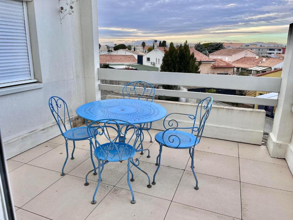 une table bleue et des chaises sur un balcon dans l'établissement Appartement 2 chambres climatisé avec piscine, à 7 min de la plage au Grau-du-Roi - FR-1-716-66, au Grau-du-Roi