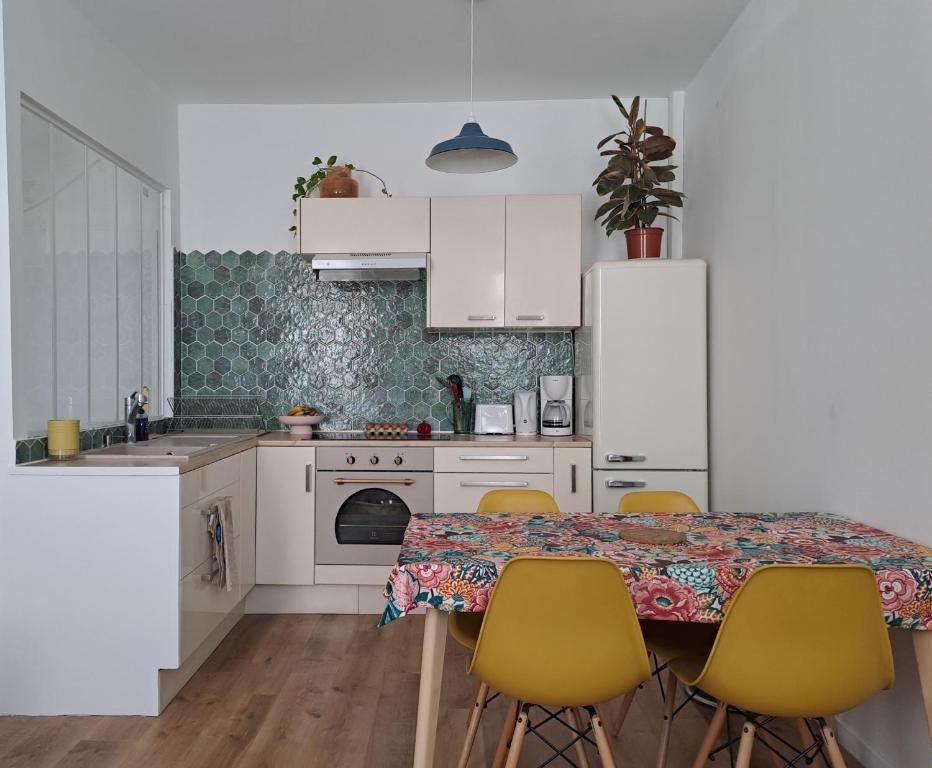 une cuisine avec des placards blancs et une table avec des chaises jaunes dans l'établissement Sweet Home Marseille, à Marseille