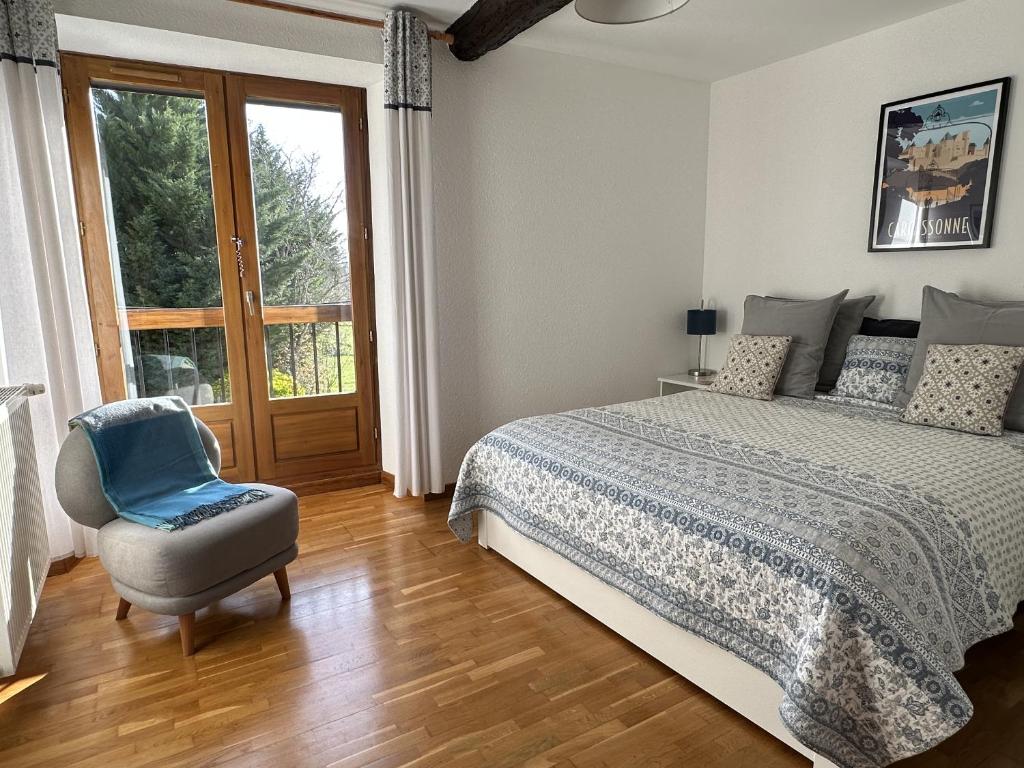 una camera da letto con un letto, una sedia e una finestra di Les Deux Chevaux Chambres d’Hôtes a Rouvenac