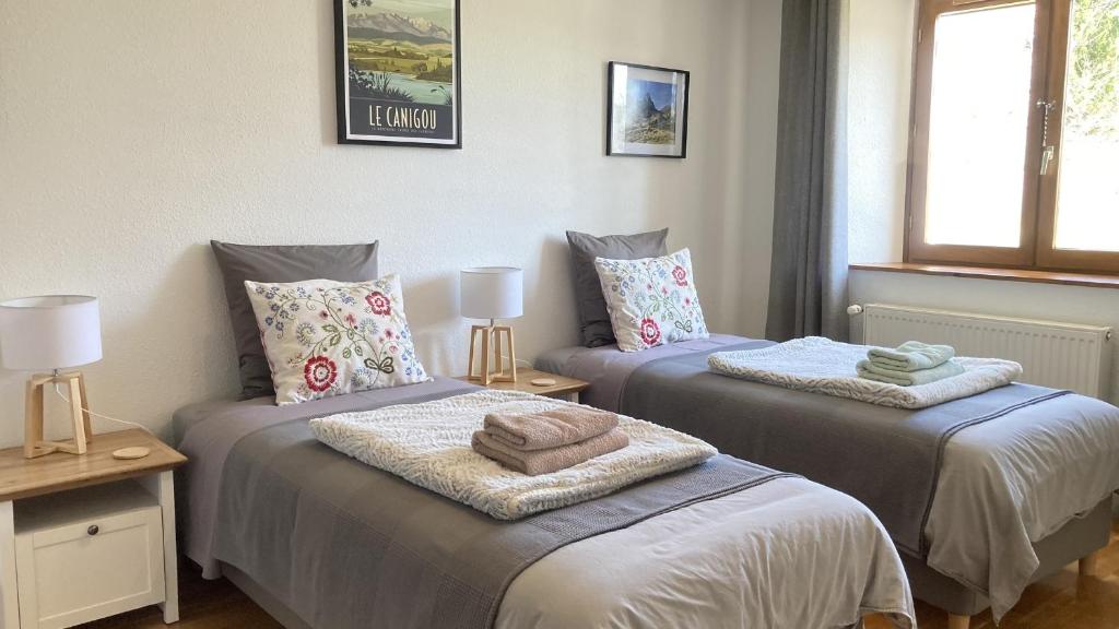 una camera da letto con due letti con asciugamani sopra di Les Deux Chevaux Chambres d’Hôtes a Rouvenac