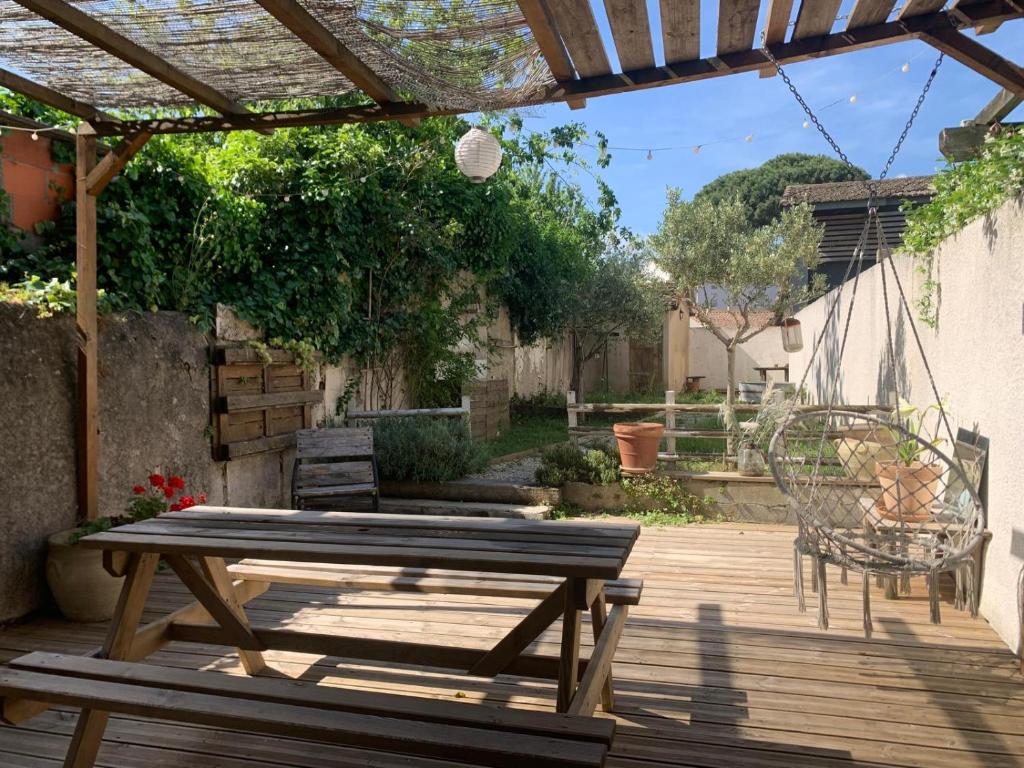 une terrasse en bois avec une table de pique-nique et des chaises. dans l'établissement La maison de Marie - Jardin arboré - Garage privatif - Netflix, à Carcassonne