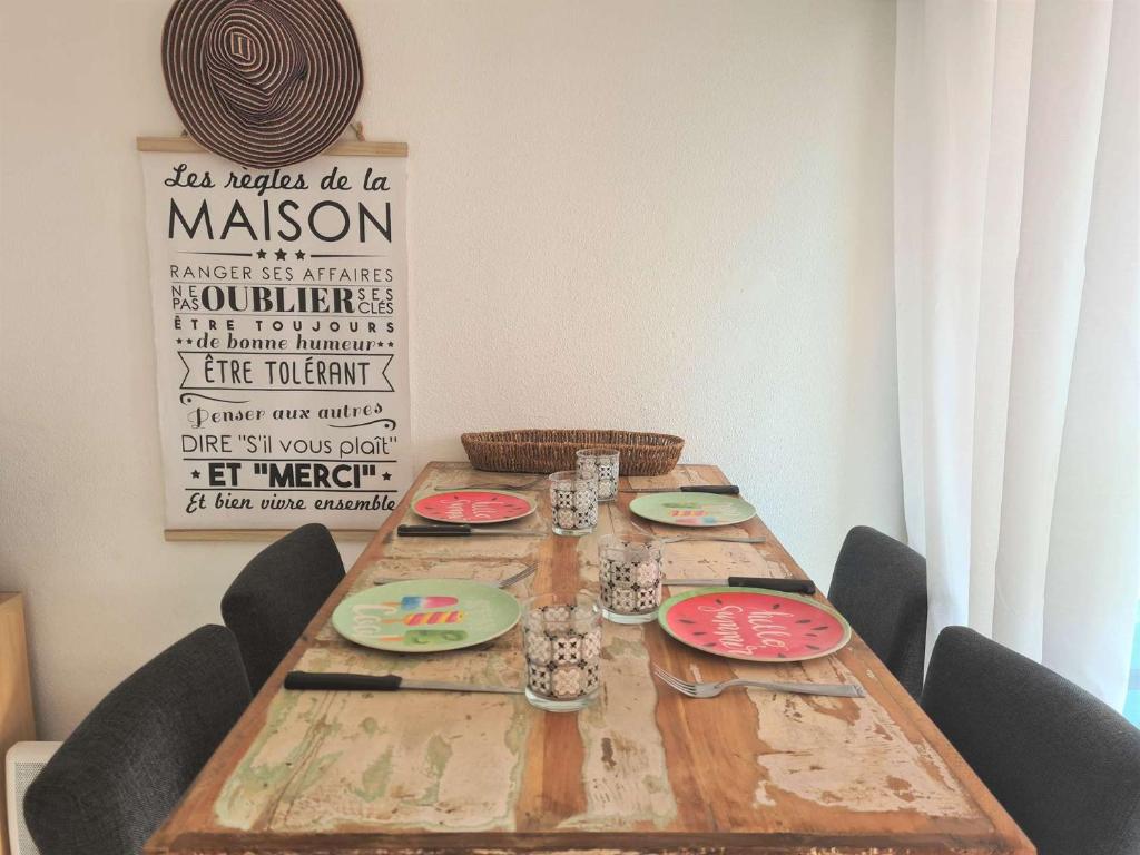 - une table en bois avec des chaises et des assiettes dans l'établissement Appt 2 pièces 4 couchages CAP D'AGDE CT045-2911, au Cap d'Agde