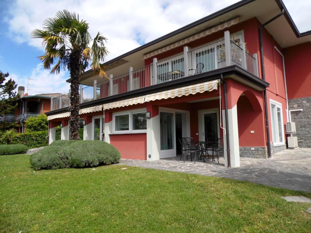 a red house with a balcony and a palm tree at Sunny Villa with Terrace in Comerio