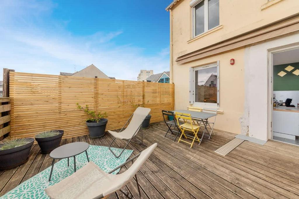 une terrasse en bois avec une table et des chaises. dans l'établissement Le Calypso -proche du centre - Terrasse et parking, à Vannes