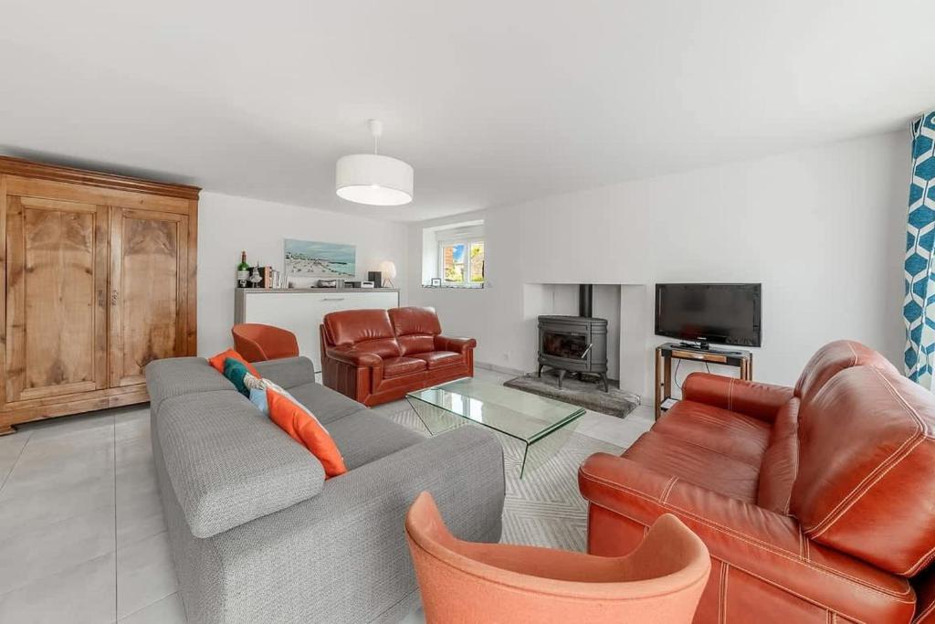 un salon avec un canapé, des chaises et une télévision dans l'établissement Maison des Flots, 3 chambres, jardin, proche plage, à Saint-Coulomb