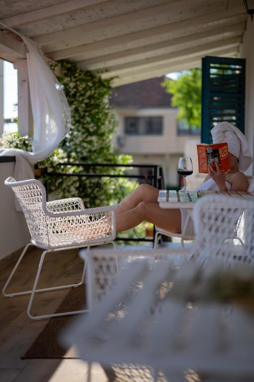 a woman laying on a chair reading a book at Guest house Mediterranea in Pakoštane