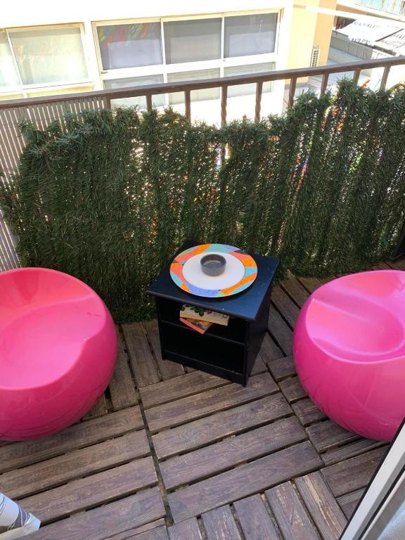 une terrasse avec deux chaises roses et un frisbee dans l'établissement A 30 pas de la Plage, à Canet