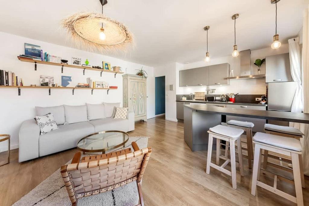 un salon avec un canapé blanc et une cuisine dans l'établissement Le Cerf-Volant, joli 2 chambres, parking, à Saint-Malo