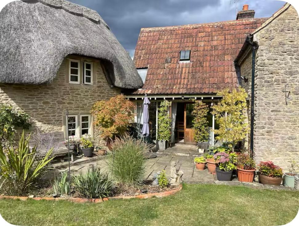 ein altes Steinhaus mit einem Strohdach in der Unterkunft Thatch Cottage B&B in Lacock